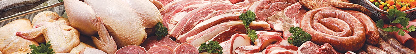 A variety of raw meats including beef cuts, a whole chicken, and steak, with parsley and lettuce.